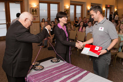 Man shakes the hand of a woman as he receives an award.