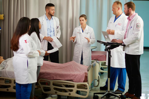 A woman speaks to a group of doctors