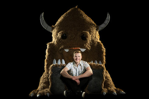 Ryan Brunty leans against a large, furry version of his yeti