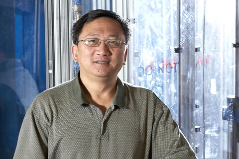 A man with glasses wearing a light gray patterned polo shirt