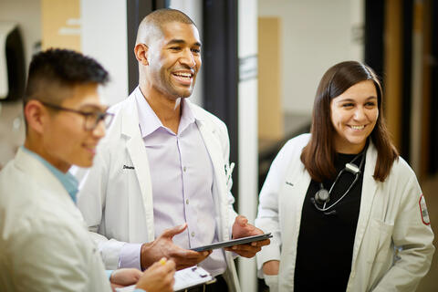 Three doctoral students look over a chart