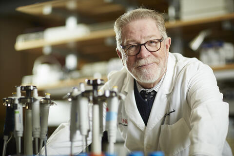 A man in a labcoat leans over various dental instruments.
