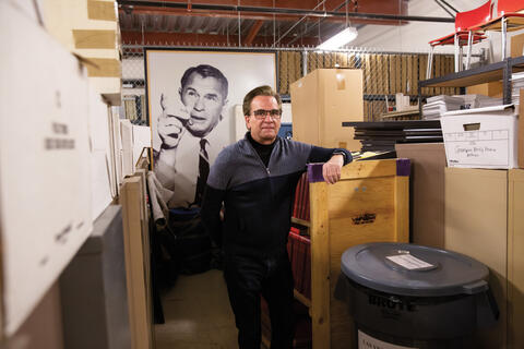 A man stands in front of a portrait