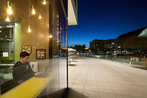 a person studying inside a building with a view of the campus outside his widow