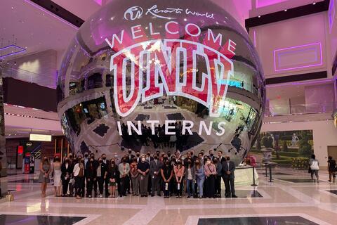 A group of students stand in front of a giant metallic sphere