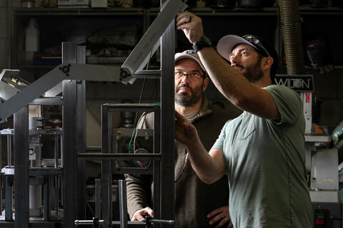 Two students work on a mechanical apparatus