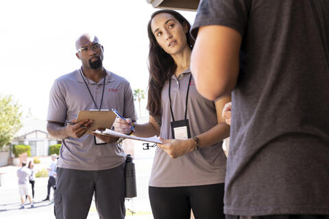 two people with clipboard talking a man