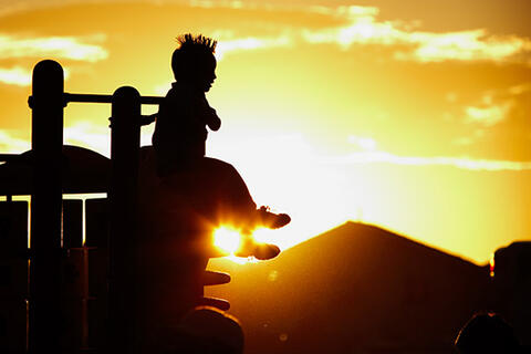 child plays on playground during sunset