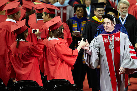 A group of graduates shaking hands with a professor