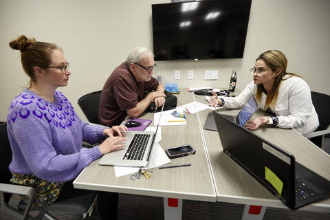 thee people working at a table