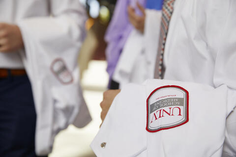 man holding doctor coat over his arm.