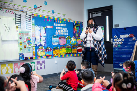 UNLV student Lushawn Threats stands at the head of the classroom and makes an X with her fingers while her students look up at her