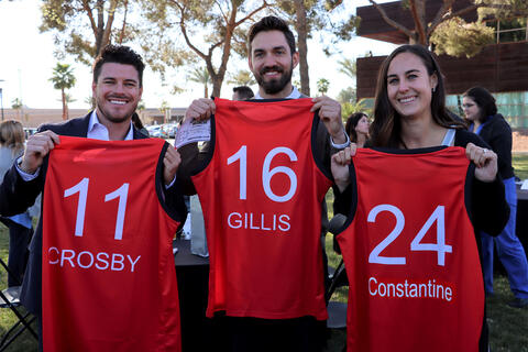 three students holding red jerseys with their names on it
