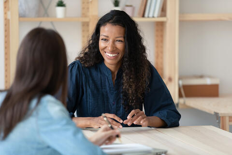 A woman talking to a person at a table.