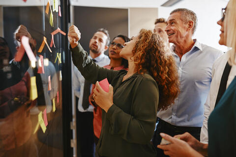 People putting sticky notes on a wall.