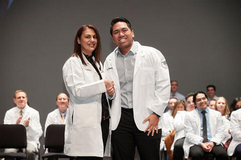 student shaking hands with professor on stage