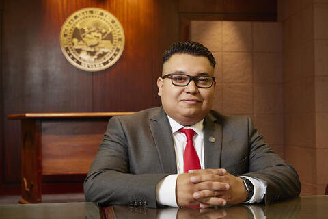 man in paneled room with seal of Nevada behind him