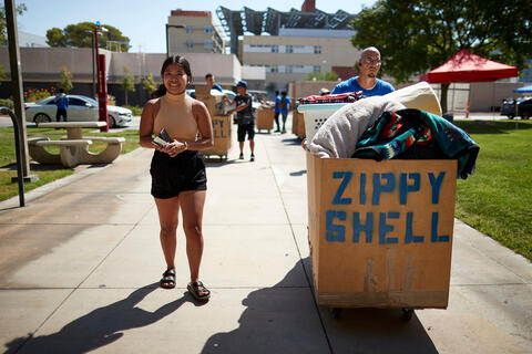 female student walking alongside moving cart