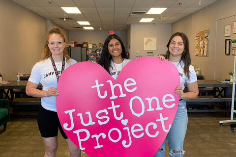 Medical students stand with large cut out of a pink heart.
