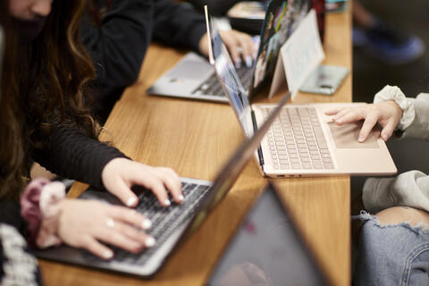 students' hands typing on laptops