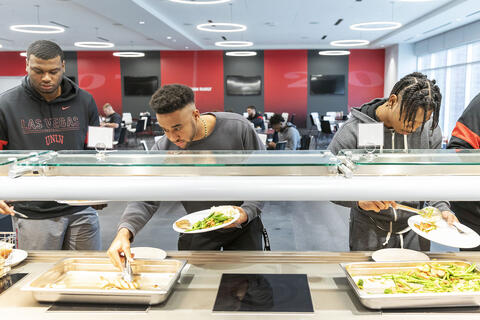 three athletes at food buffet