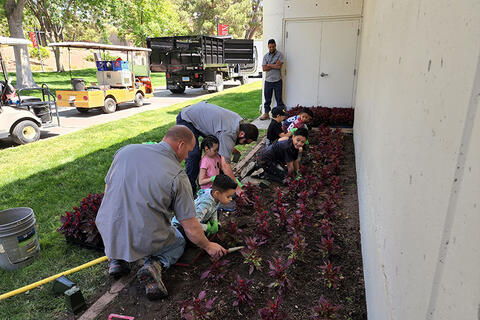 U-N-L-V employees with children showing them irrigation installations