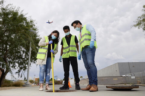 researchers standing over sewer manhole