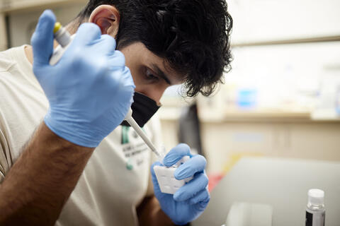 student working in campus lab with pipette