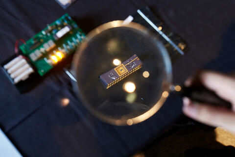 hand holding a magnifying glass over a computer motherboard piece