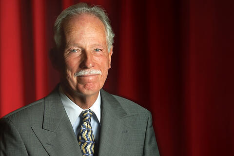 man in suit posing in front of red backdrop