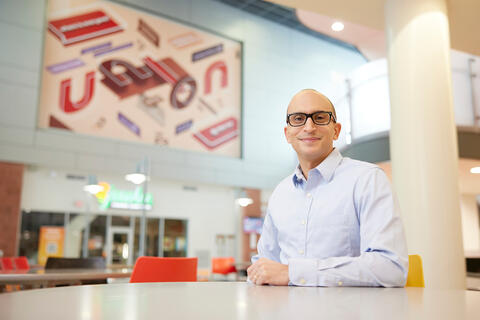 man with glasses sits at table inside building