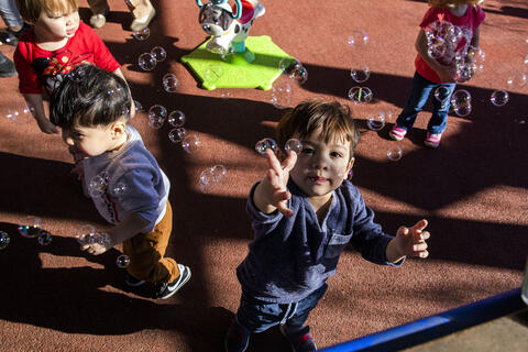 toddlers on playground with trying to catch bubbles