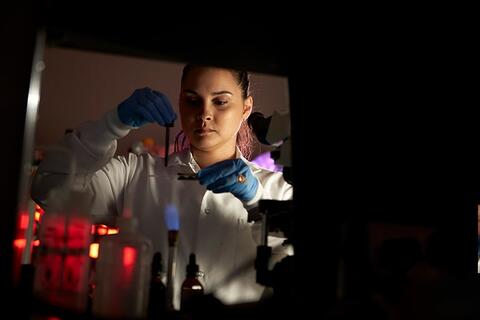 Student conducting research drops liquid onto a slide