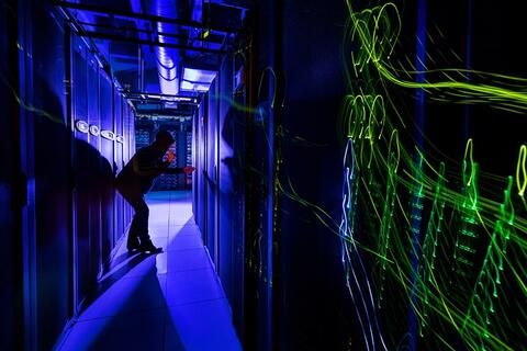 Hacker, dressed in black, inside a networking room