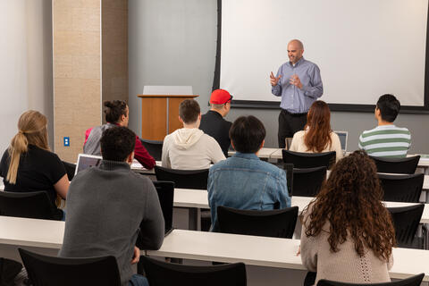 man standing and teaching in front of full classroom