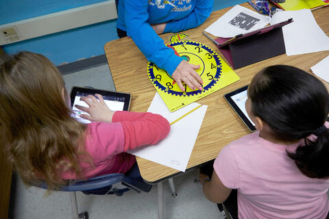 detail shot of 3 schoolchildren in classroom working