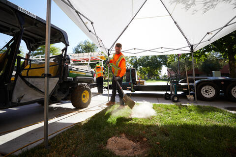 man digging in ground under white canopy