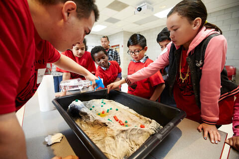 group of young students performing science experiment