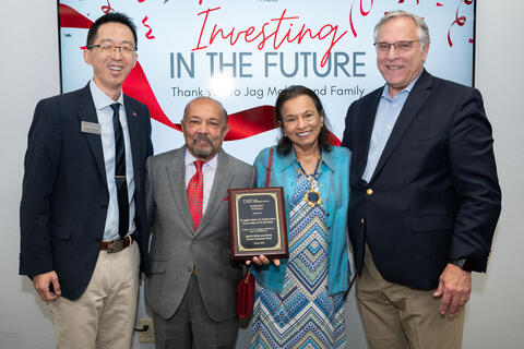 four people posing with a plaque