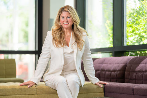 woman dressed in white blazer and pants sitting on ottoman