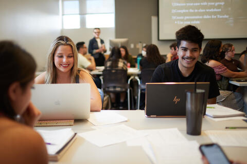 two students using laptops in classroom