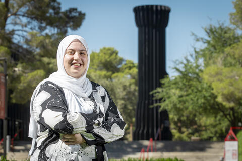 woman poses with arms crossed in front of flashlight sculpture
