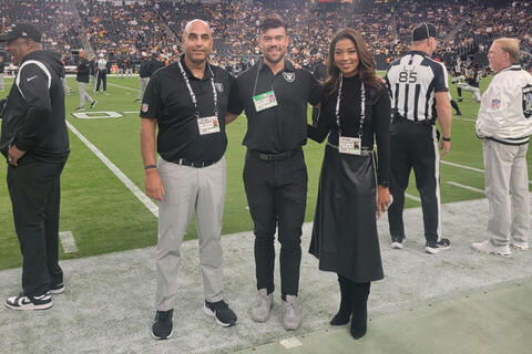Medical student Cameron Harris (center) on Allegiant Stadium's sideline with Raiders chief medical officer, Dr. Navdeep Singh (left), and team president, Sandra Douglass Morgan (right).