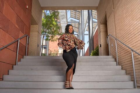 woman in fabulous outfit posing at bottom of staircase