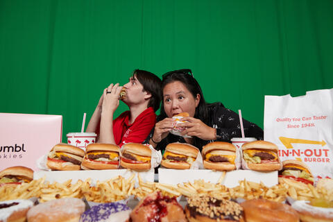 two people eating and surrounded by various fast food items