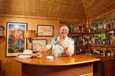 man at tiki bar holding cigar