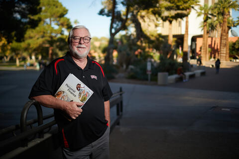 man in glasses outside holding book