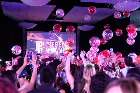 crowd catching balloon falling from the ceiling