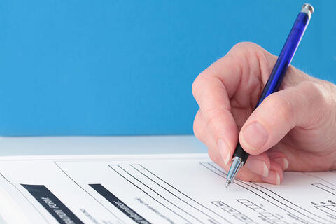 A person writing down on a form using a pen