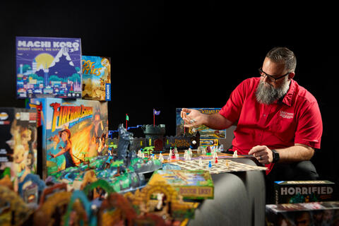 man sitting at a table surrounded by various board games